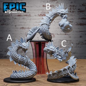 May include: Three unpainted grey resin miniature figurines labelled A, B, and C, each depicting a serpentine creature with scales, dorsal fins, and a fanged head. Figure B features a cloud-like effect near its mouth, while A and C are coiled.