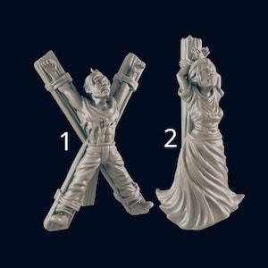 May include: Two gray resin figurines. One depicts a person tied to an X-shaped wooden structure, arms outstretched. The other shows a person tied to a vertical wooden post, arms raised. Both figures have distressed expressions.