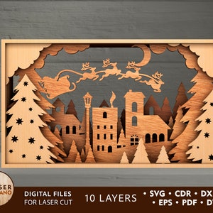 May include: A laser cut wooden Christmas scene with a town, trees, and Santa Claus flying in a sleigh with reindeer. The scene is made up of 10 layers and is ready to be assembled.
