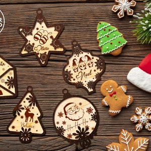 Puede incluir: Surtido de adornos navide&ntilde;os de madera con varios dise&ntilde;os, incluyendo una estrella, un &aacute;rbol, una carta a Santa Claus y una cabeza de Santa Claus. Los adornos est&aacute;n decorados con copos de nieve, renos y otros detalles festivos.