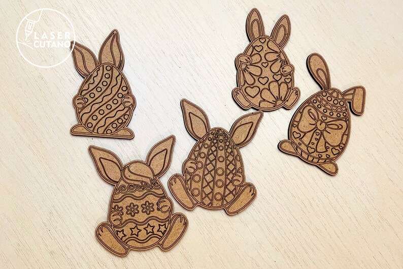 May include: Five wooden Easter bunny cutouts with different patterned eggs. The bunnies are holding the eggs in their front paws. The eggs are decorated with hearts, stripes, polka dots, and flowers.