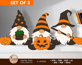 Pode incluir: Conjunto de três gnomos de Halloween com chapéus listrados preto e laranja. Um gnomo segura um caldeirão, outro uma abóbora e outro uma vassoura.