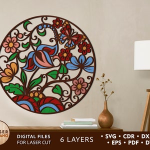 May include: A round, multi-layered, laser cut design featuring a floral pattern with a butterfly in the center. The design is in shades of red, blue, green, yellow, and pink. The design is for laser cutting and has 6 layers. Digital files for laser cut are included.  SVG, CDR, DXF, AI, EPS, PDF, and DWG files are included.