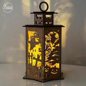 May include: A wooden Halloween lantern with intricate cut-out designs. The lantern features a spooky scene with a haunted house, witch, pumpkins, and a full moon. The lantern has a handle and is illuminated from within, creating a warm glow.