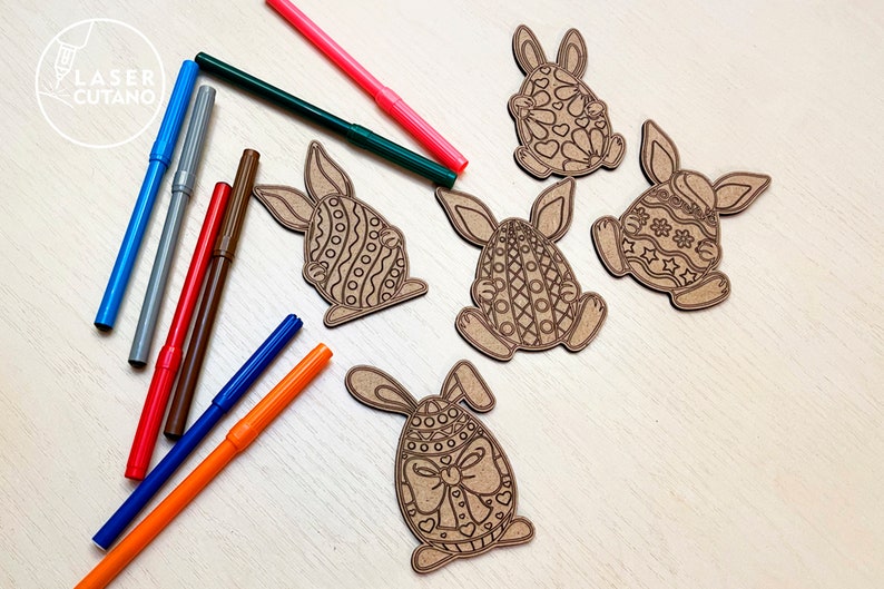 May include: Five unfinished wooden Easter bunny ornaments with intricate designs. The bunnies are shaped like eggs and have different patterns. A set of colorful markers are also included.