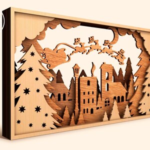 May include: A wooden Christmas scene with a town, trees, and Santa Claus flying in a sleigh with reindeer. The scene is cut out of wood and has a 3D effect.