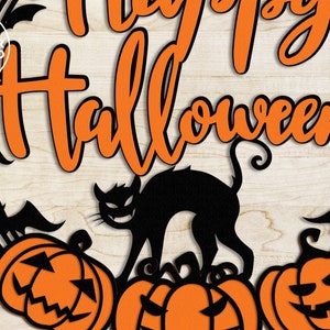 May include: A black silhouette of a cat with a spooky grin, standing on top of three orange pumpkins with carved faces. The text "Happy Halloween" is written in orange letters on a black wreath with bats.