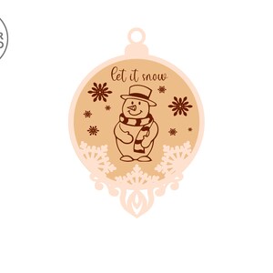 Puede incluir: Un adorno navide&ntilde;o de madera con forma de bola con un mu&ntilde;eco de nieve y copos de nieve. El adorno est&aacute; pintado en tonos marrones y blancos y tiene el texto "let it snow" en &eacute;l.