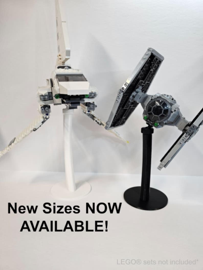 May include: Two LEGO Star Wars spaceship models on display stands. The white spaceship is on a white stand and the black spaceship is on a black stand. The text "New Sizes NOW AVAILABLE!" is at the bottom of the image.