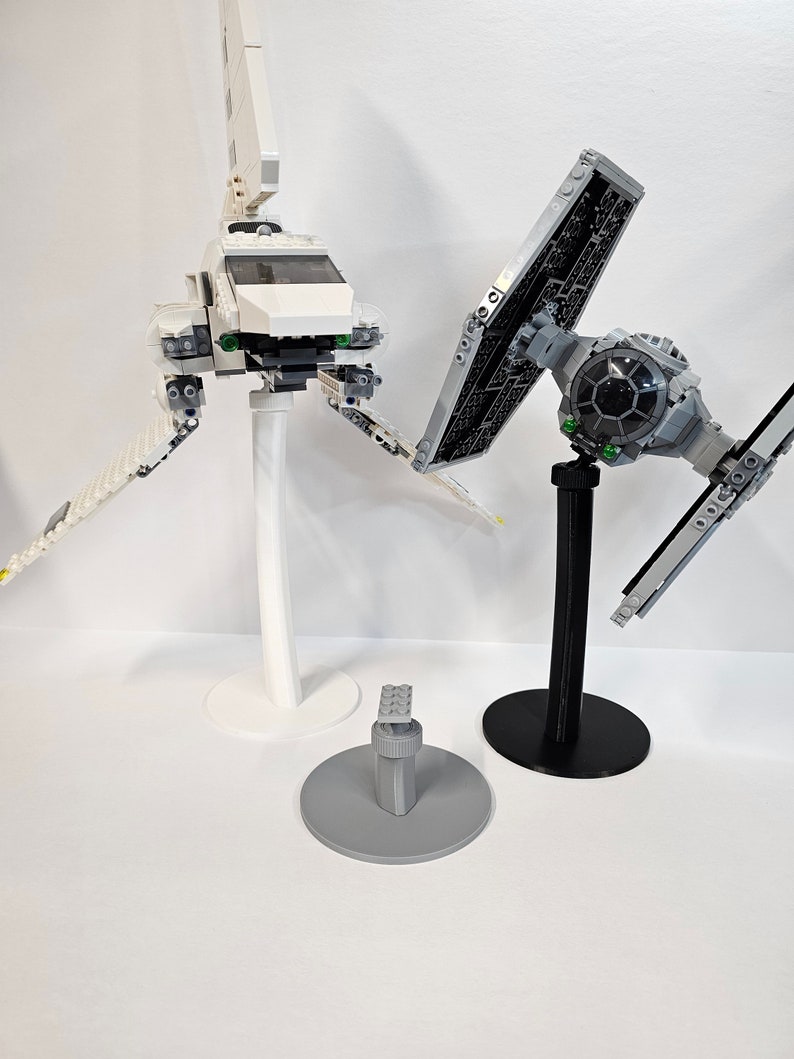 May include: Two Star Wars Lego spaceship models on display stands. The white spaceship is on a white stand and the black spaceship is on a black stand.