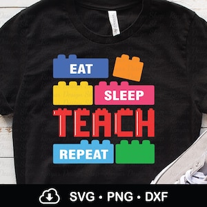 May include: Black t-shirt with a colorful graphic design. The design features the words "EAT SLEEP TEACH REPEAT" in a block-style font, with each word on a different colored block. The shirt is made of a soft material.