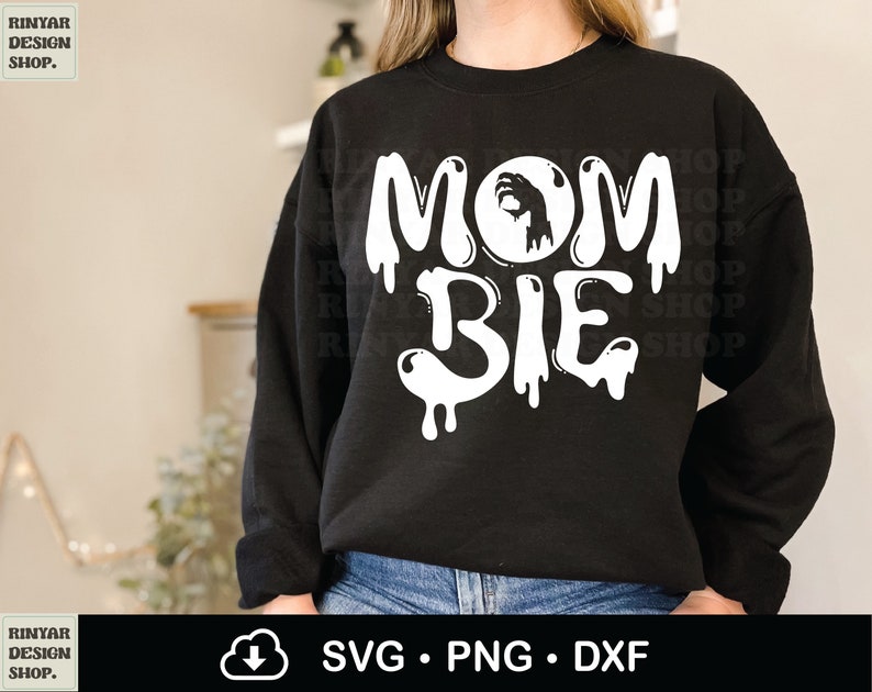 May include: Black sweatshirt with white dripping text that reads "MOM BIE" with a white hand inside a circle above the word "MOM".