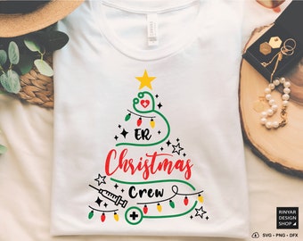 May include: White t-shirt with a green Christmas tree design. The tree is decorated with red and yellow lights and a red heart with a white cross. The text "ER Christmas Crew" is written on the tree.
