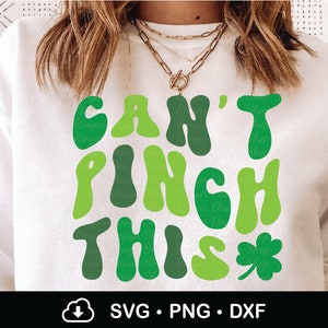 Peut inclure: Sweat-shirt blanc avec un texte vert qui dit "Can't Pinch This" dans une police r&eacute;tro. Un tr&egrave;fle vert se trouve &agrave; droite du texte.