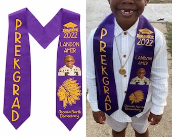 May include: Purple and gold pre-kindergarten graduation sash with the words "PREKGRAD" in yellow letters. The sash has a photo of a young boy, the text "Class of 2022", "Landon Amir", and the name of the school, "Osceola North Elementary".
