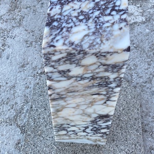 May include: A rectangular pedestal made of polished stone featuring a complex, swirling pattern of white, cream, and deep dark purple veins throughout its entire surface. The object has a smooth, reflective finish and a solid, block-like structure.