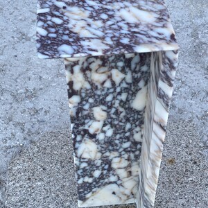 May include: A C-shaped side table crafted from polished stone featuring a complex, high-contrast pattern of deep purple, dark brown, and creamy white veining throughout the entire surface, creating a dense, marbled appearance on all visible sides.