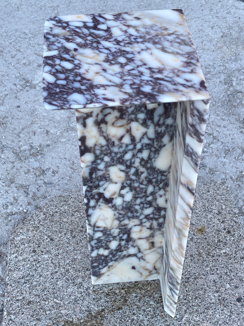 May include: A C-shaped side table crafted from polished stone featuring a complex, high-contrast pattern of deep purple, dark brown, and creamy white veining throughout the entire surface, creating a dense, marbled appearance on all visible sides.