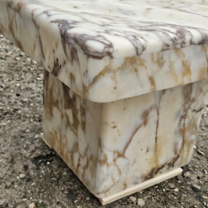May include: A square side table constructed from polished white marble with prominent brown and grey veining throughout. The table features a thick, overhanging top surface supported by a solid, block-style pedestal base with smooth, rounded edges.
