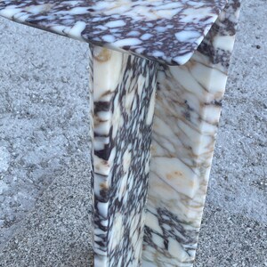 May include: A C-shaped side table constructed from polished marble featuring a distinct pattern of white, cream, and deep purple-brown veining. The structure consists of a flat rectangular top surface supported by a vertical base panel.