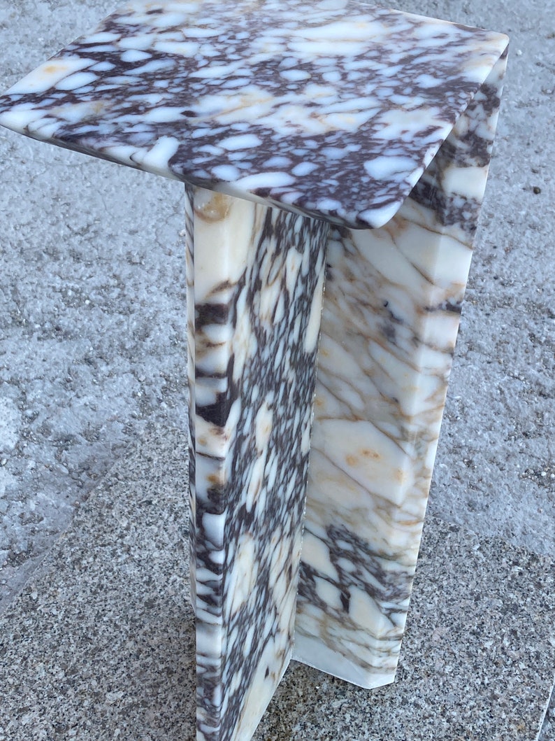 May include: A C-shaped side table constructed from polished marble featuring a distinct pattern of white, cream, and deep purple-brown veining. The structure consists of a flat rectangular top surface supported by a vertical base panel.