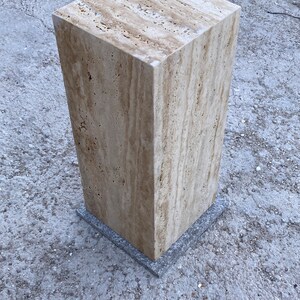 Puede incluir: Un pedestal cuadrado de travertino marr&oacute;n claro con una base de piedra gris. El pedestal est&aacute; hecho de piedra natural y tiene una superficie rugosa y texturizada.