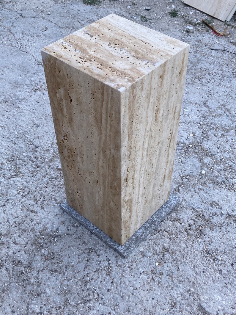 Puede incluir: Un pedestal cuadrado de travertino marr&oacute;n claro con una base de piedra gris. El pedestal est&aacute; hecho de piedra natural y tiene una superficie rugosa y texturizada.