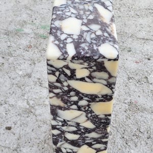 May include: A rectangular, marble-like object with a unique pattern of cream, dark brown, and white veining. The stone has a polished surface and a smooth texture. The object is likely a decorative item or a piece of home decor.