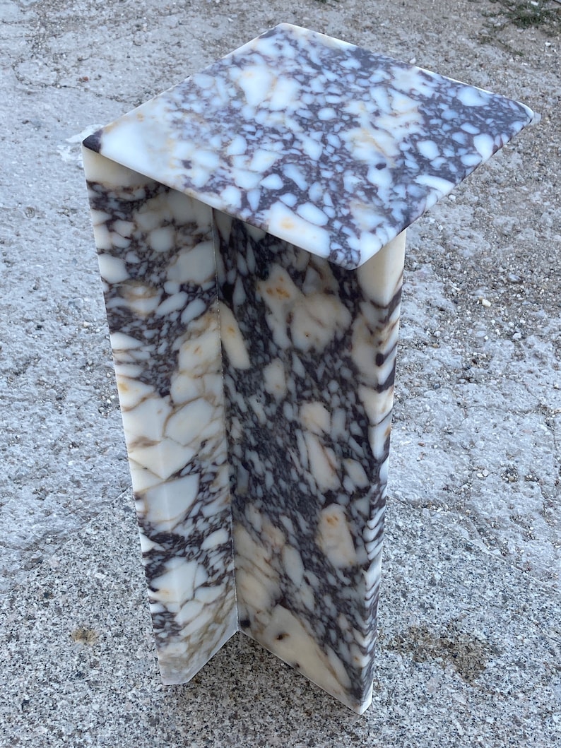 May include: A tall, L-shaped pedestal stand crafted from polished stone with a distinct brecciated pattern. The surface features a complex mix of white, cream, and deep purple-brown angular fragments embedded in a smooth, glossy finish.