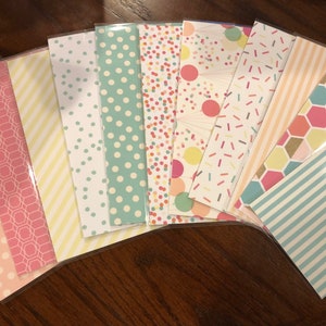 May include: A set of ten decorative paper sheets with various patterns. The patterns include polka dots, stripes, confetti, and honeycomb designs in pink, yellow, blue, and white.