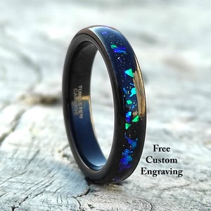May include: Black tungsten carbide ring with a dark blue inlay featuring iridescent green and blue flecks. The ring has the text "Tungsten Carbide" on the side. The image also includes the text "Free Custom Engraving".