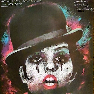 May include: A vintage film poster for the movie "Cabaret" starring Liza Minnelli and Michael York. The poster has a black background with a colourful image of Liza Minnelli wearing a black top hat and white face paint. The text on the poster is in red and white.