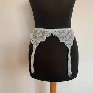 May include: A light blue lace suspender belt with satin ribbon straps.