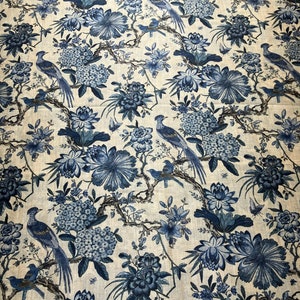 Può includere: Un tessuto bianco con un motivo floreale blu con uccelli e fiori. Il tessuto ha una texture di lino sottile.