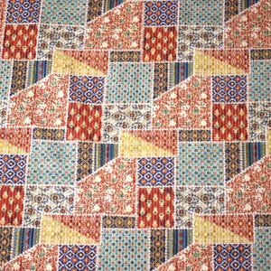 Peut inclure: Un tissu à motifs avec un motif patchwork. Le motif comprend des carrés, des triangles et des rectangles dans une variété de couleurs, notamment le rouge, le bleu, le jaune et le vert, créant un aspect texturé.