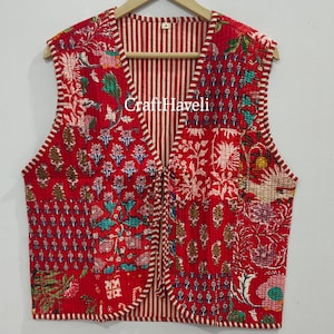 以下が含まれることがあります： 赤いキルティングベストは、花柄とストライプの裏地が付いています。ベストはVネックで、袖なしです。ベストの前面には「CraftHaveli」の文字が印刷されています。
