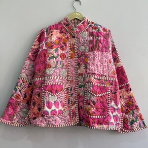 May include: A quilted jacket featuring a patchwork design in shades of pink, white, and green with floral and strawberry patterns. The jacket has a mandarin collar, long sleeves, two front pockets, and white and pink striped trim. Text reads CraftHaveli.