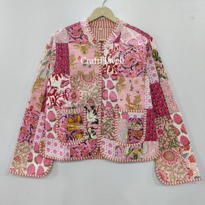 Puede incluir: Una chaqueta acolchada rosa y blanca con estampado floral y cierre de cremallera. La chaqueta tiene un cuello mandarín y dos bolsillos. El texto "Craft Haveli" es visible en la parte delantera de la chaqueta.