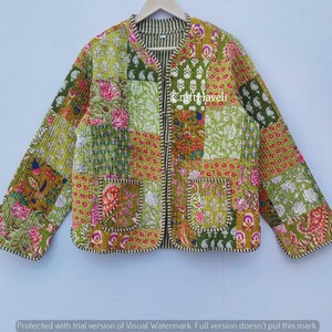 May include: A patchwork jacket with floral and geometric patterns in green, pink, and gold. The jacket has a round collar, two front pockets, and a zip closure. The jacket is hanging on a wooden hanger.