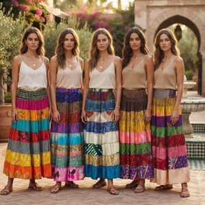 Puede incluir: Cinco personas con camisetas de tirantes beige y faldas largas de varios niveles hechas de paneles de tela multicolor. Cada falda presenta una combinación única de patrones vibrantes, incluyendo diseños florales, geométricos y abstractos.