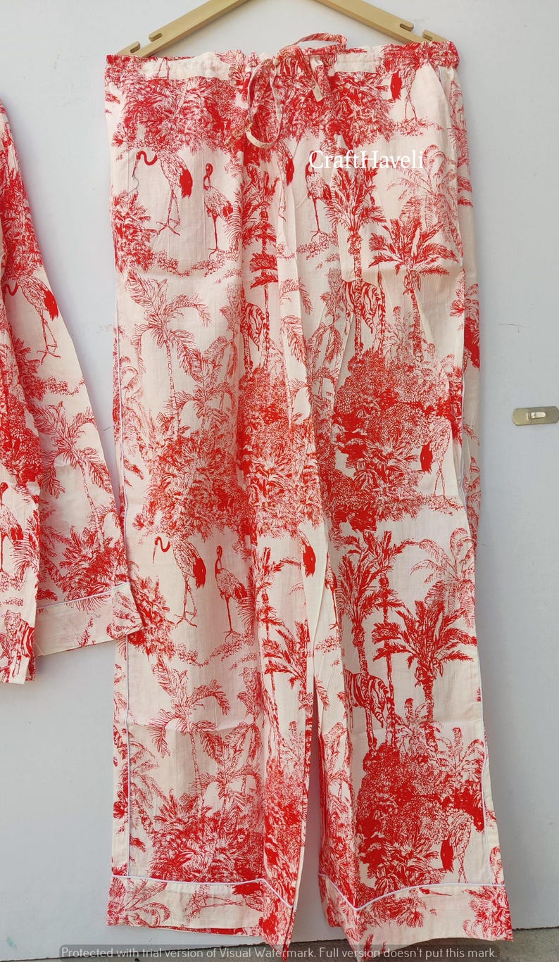 May include: White pajama pants with a red and white print of palm trees and birds. The pants have a drawstring waist.