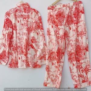May include: Red and white pajama set with a floral print featuring birds. The top has a button-up front and long sleeves. The pants have an elastic waistband.
