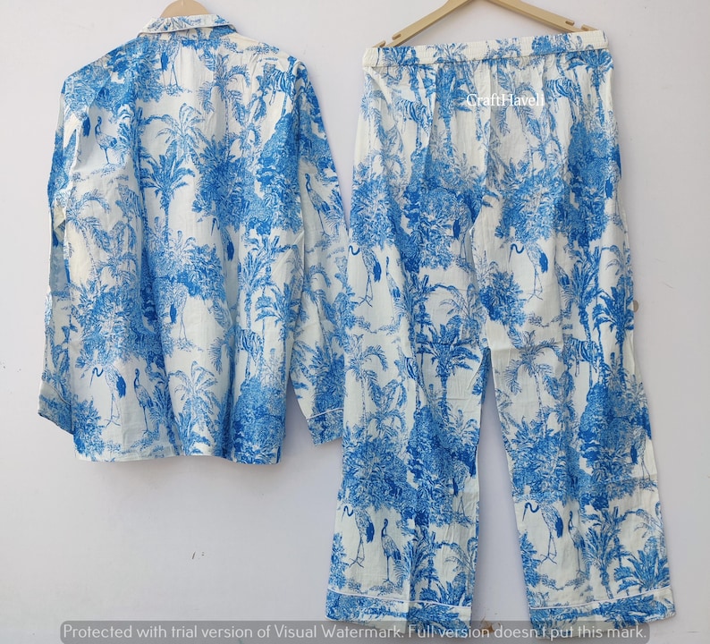 May include: A white pajama set with a blue and white palm tree and bird print. The set includes a long-sleeved shirt and pants.