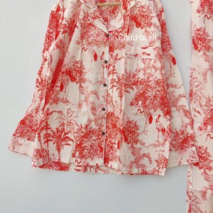 May include: A white pajama top with red and white floral print featuring palm trees and birds. The top has a button-up front and long sleeves. The text "Craft Haveli" is visible on the top.