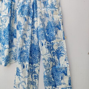 May include: White pajama pants with a blue and white print of palm trees, birds, and tigers. The pants have an elastic waistband and a drawstring.