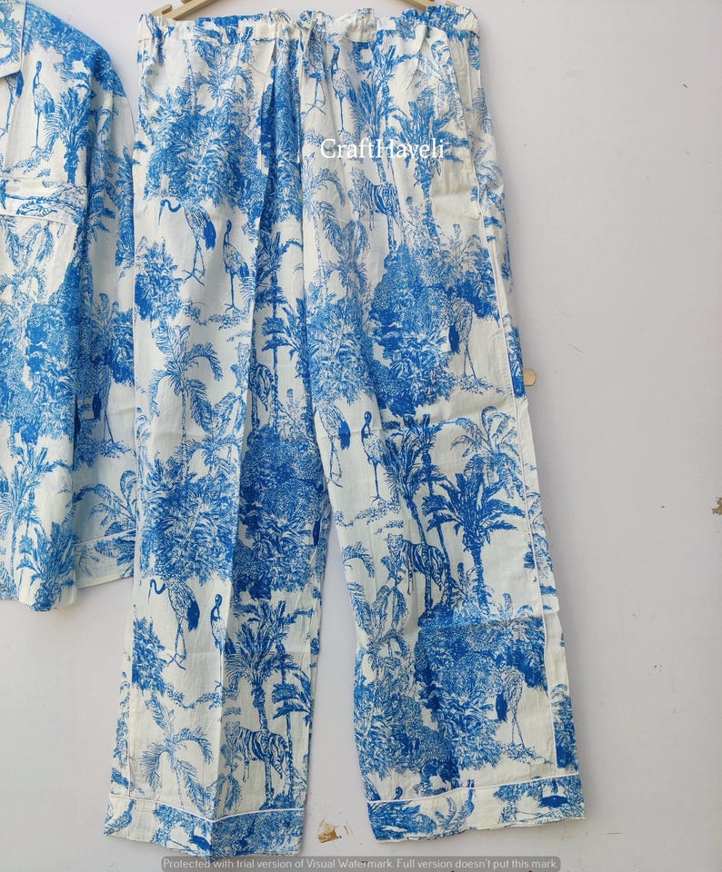 May include: White pajama pants with a blue and white print of palm trees, birds, and tigers. The pants have an elastic waistband and a drawstring.