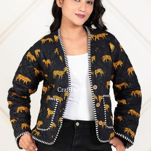 Puede incluir: Chaqueta acolchada negra con estampado de leopardo. La chaqueta tiene un ribete a rayas blancas y negras en los bordes y bolsillos. La chaqueta está abotonada y tiene el texto "Craft Haveli".