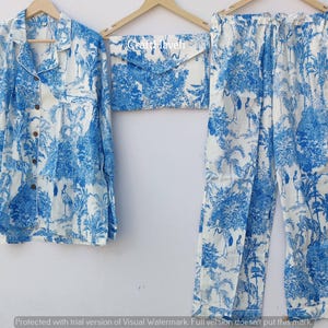 May include: A white pajama set with a blue and white floral print. The set includes a long-sleeved shirt with a collar and a pair of pants.