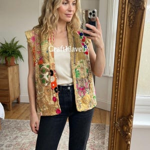 May include: A sleeveless vest in a light gold tone featuring intricate patchwork embroidery with colorful floral and geometric patterns, metallic thread accents, and small circular embellishments. The text CraftHaveli is visible.