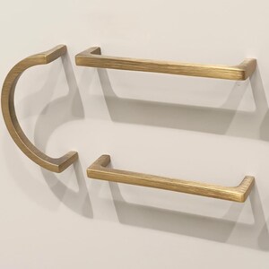 May include: Four gold-toned cabinet pulls, two are curved and two are straight.